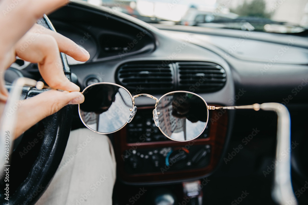 sunglasses in the hands of the driver against the background of the car interior.