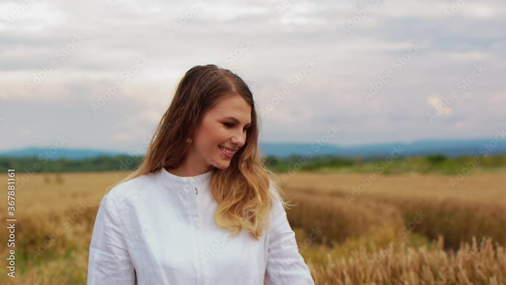 A young girl walking through a field wheat ears. Beautiful carefree woman enjoying nature and touching with hand in wheat field A young girl walking through a field wheat ears. Beautiful carefree woman enjoying nature and touching with hand in wheat field