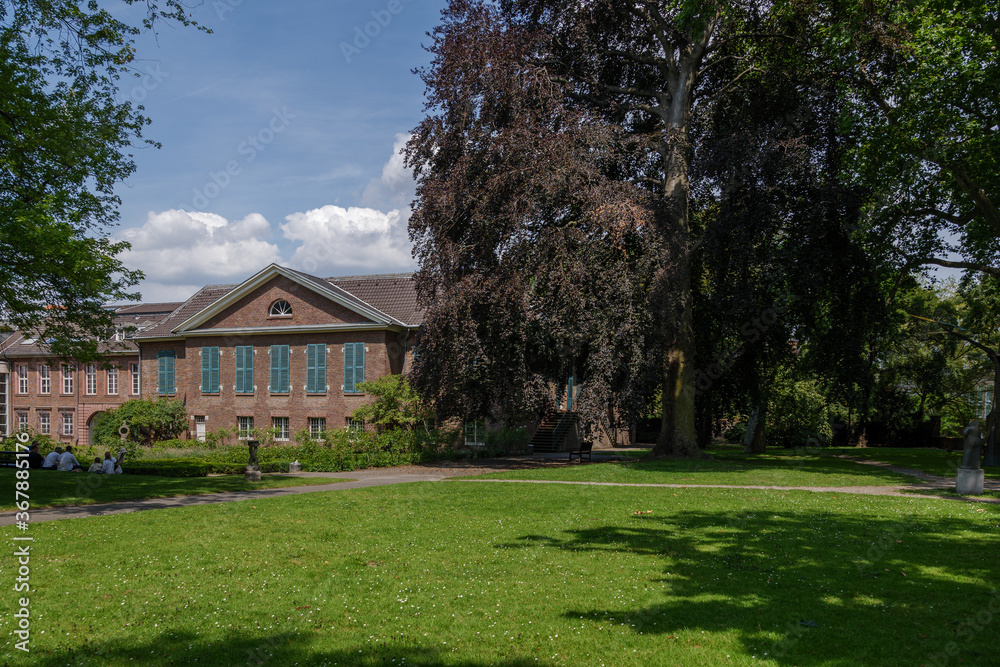 Outdoor sunny and shady scenery around Rosengarten, tranquil garden nearby Stadtmuseum Düsseldorf with historical brick architecture, in Germany. Outdoor sunny and shady scenery around Rosengarten, tranquil garden nearby Stadtmuseum Düsseldorf with historical brick architecture, in Germany.