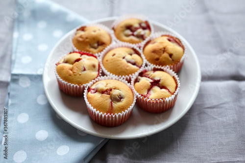 Strawberry muffins with fresh berries on white plate on linen napkin background