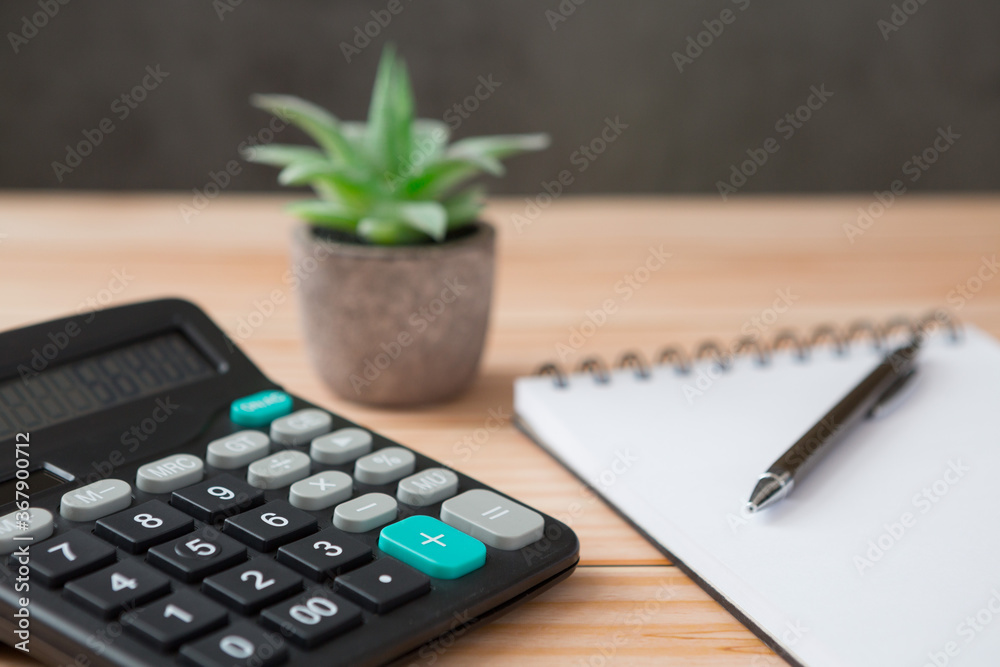 Notebooks, calculator, pens, cactus  on wooden desks and loft walls with sunlight and copy space