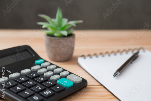 Notebooks, calculator, pens, cactus on wooden desks and loft walls with sunlight and copy space