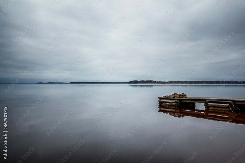 Mirror surface of the lake with the sky reflected in it. Old wooden bridge. Beautiful Karelian landscape. Space for text.