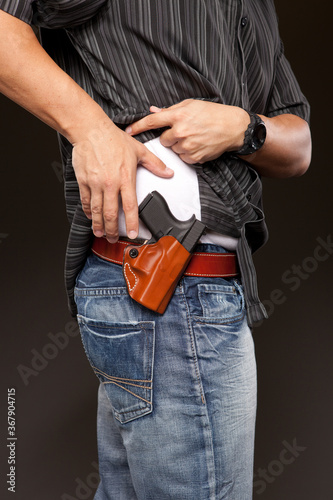 Man lifts his shirt and is about to draw his concealed carry pistol.