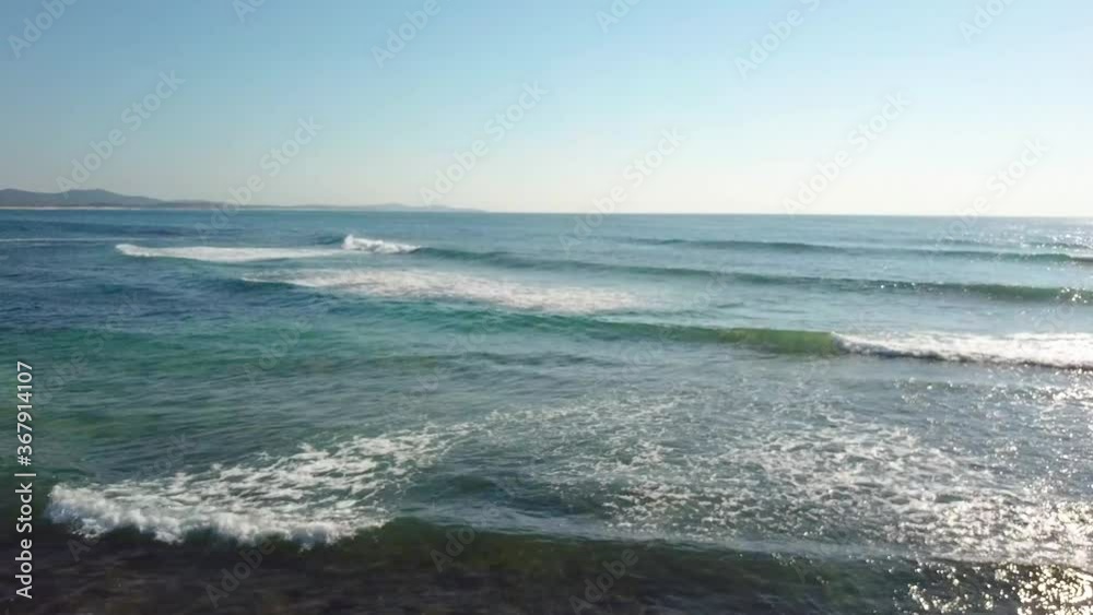 Drone Aerial Of Fisherman On Shallow Rocky Beach Shore With Ocean Waves Crashing In Morning Sunlight Drone Aerial Of Fisherman On Shallow Rocky Beach Shore With Ocean Waves Crashing In Morning Sunlight