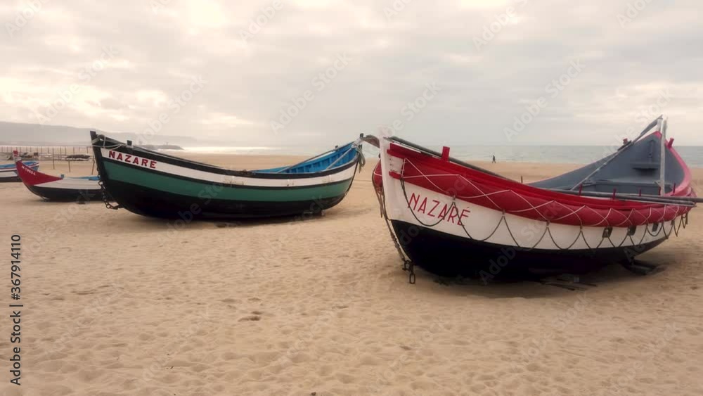 Traditional fishing wooden boats on the sandy beach of Nazare in Portugal Traditional fishing wooden boats on the sandy beach of Nazare in Portugal