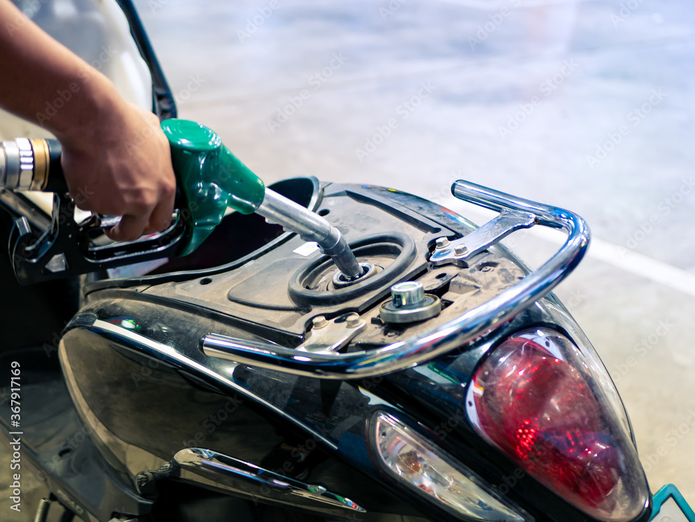 Gas station employee refilling fuel to a motorbike