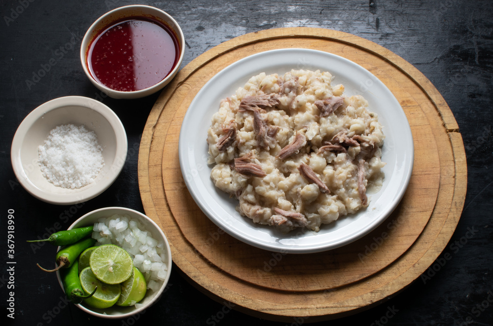 Pozole seco, typical food from colima Mexico accompanied by lemon, onion, green chili, sauce, salt on a circular plate