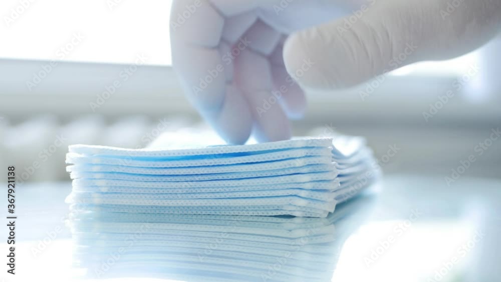 Doctor Counting and Checking Pack of Surgical Masks One by One in Hospital Room Doctor Counting and Checking Pack of Surgical Masks One by One in Hospital Room