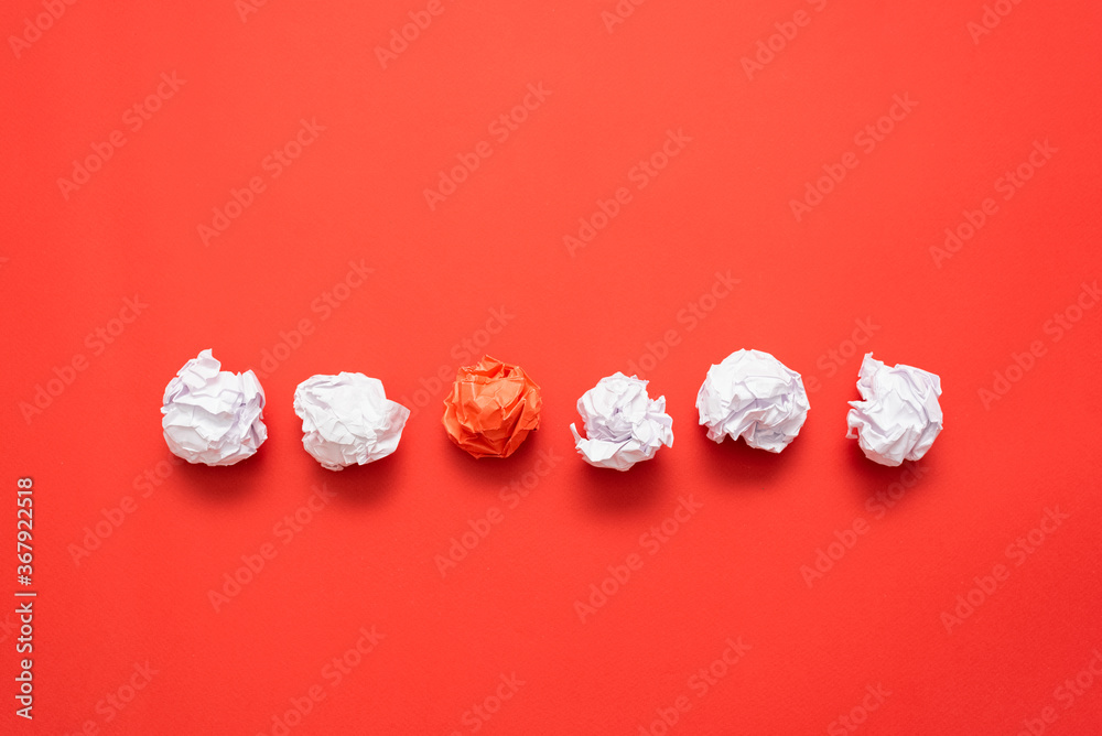 Crumpled red paper leaf ball between white balls on the red flat lay background with copy space. Crumpled red paper leaf ball between white balls on the red flat lay background with copy space.