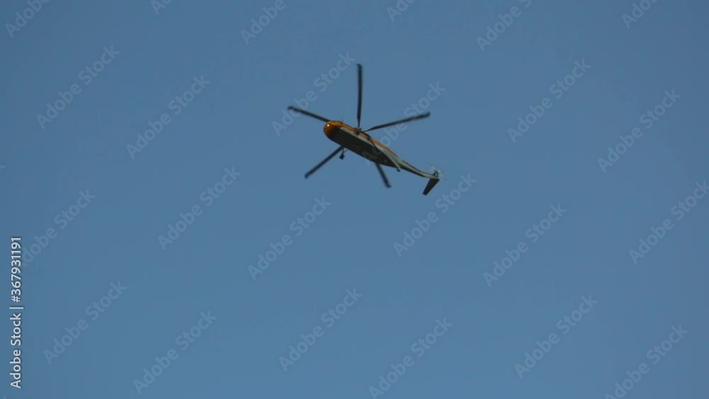 A firefighting helicopter flies directly overhead searching for water for nearby forest fire wildfire and disappears behind trees A firefighting helicopter flies directly overhead searching for water for nearby forest fire wildfire and disappears behind trees
