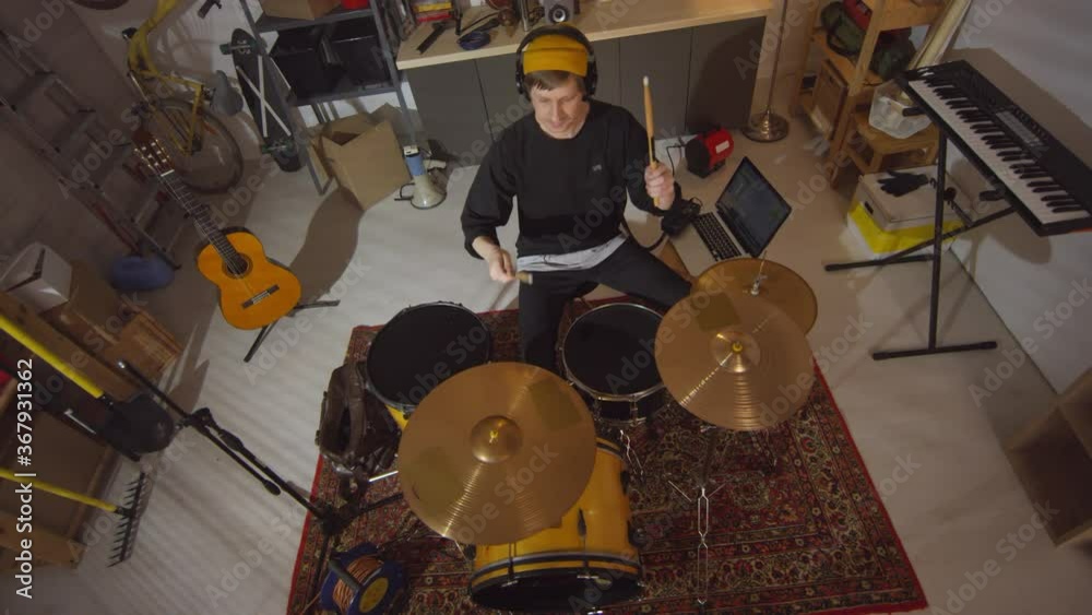 High angle view slowmo shot footage of modern musician practicing playing drums in garage studio