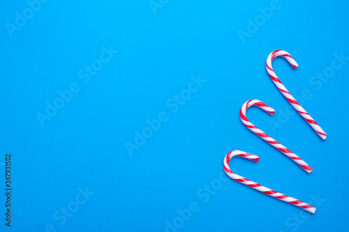 White and red candy canes on a blue background, copy space