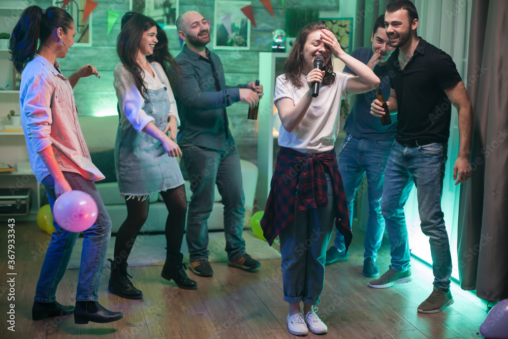 Young woman can't believe she's doing karaoke at her friends party.