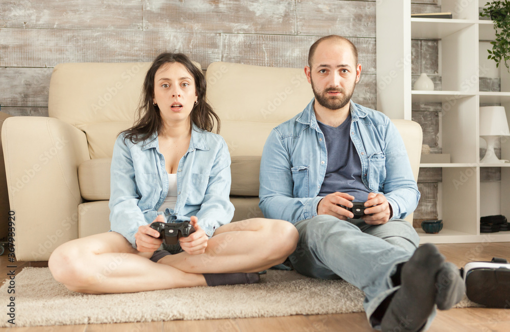 Young couple playing video games in living room. Young couple playing video games in living room.