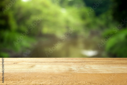 Empty table top on blur green and river background.