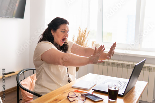 A woman sits at home at a desk, works with a laptop in social networks.