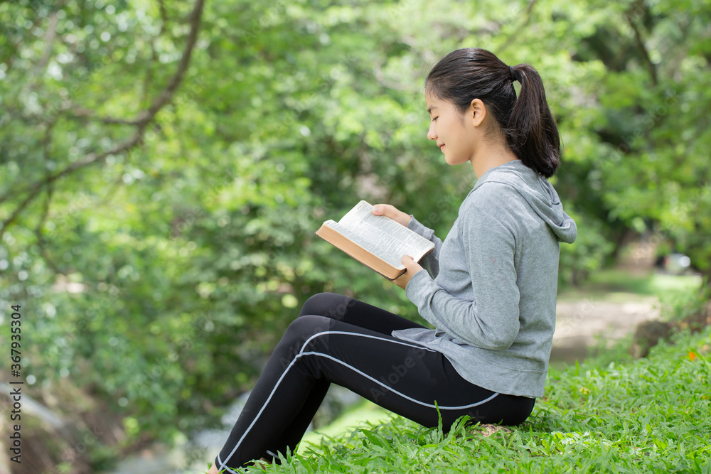 Pretty young woman reading bible in park. Reading abook.The concept of God's bible is based on faith and spirituality. Pretty young woman reading bible in park. Reading abook.The concept of God's bible is based on faith and spirituality.