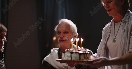 Happy family celebrating birthday. Old moustached man blowing out candles on birthday case while his grown kids and grandchildren are clapping and cheering - real people, celebration concept 4k video photo