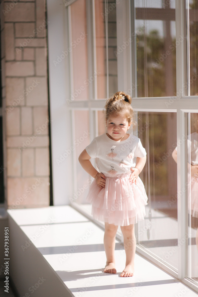 Cute little girl three year old in dress posing for photograper in studio. Beutiful little girl sits on windowsill Cute little girl three year old in dress posing for photograper in studio. Beutiful little girl sits on windowsill