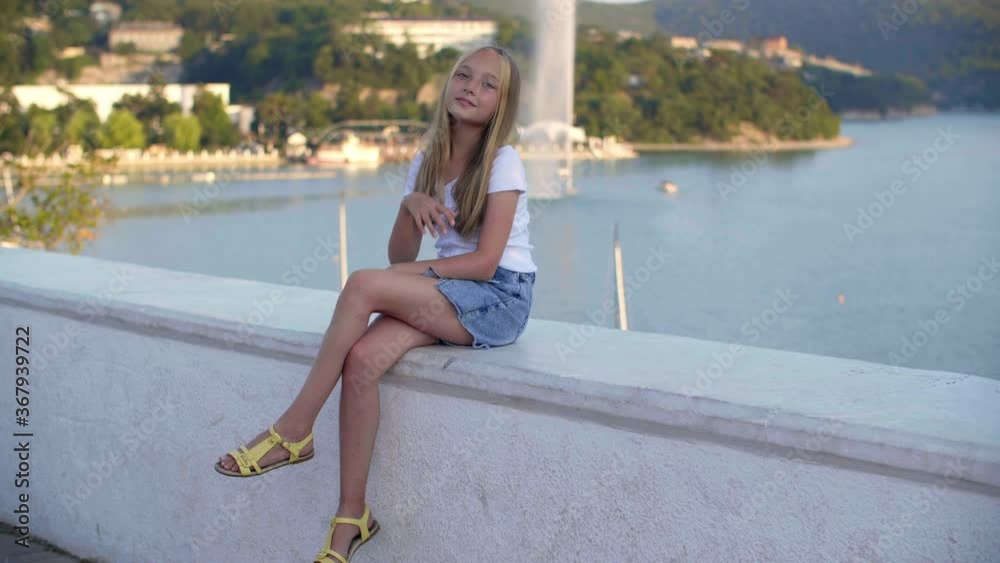 Beautiful teen girl on sea bay lake and green highlands landscape. Cute teenager girl posing to camera on lake panorama with yachts and boats