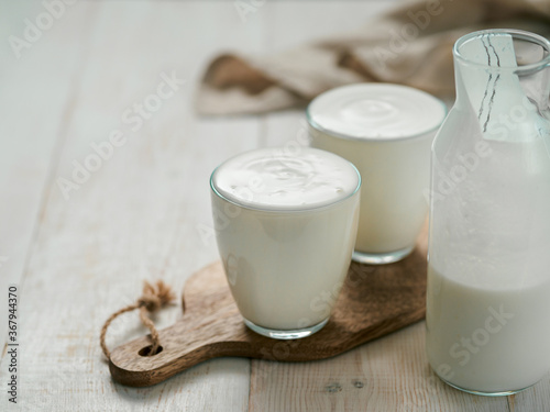 Kefir, buttermilk or yogurt with probiotics. Yogurt in glass on white wooden background. Probiotic cold fermented dairy drink. Gut health, fermented products, healthy gut flora concept. Copy space photo