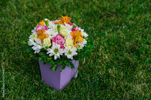Картината върху платно bouquet of colorful flowers in hatbox on lawn. place for text.