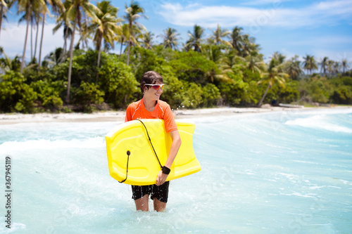 Photography Child surfing on tropical beach. Surfer in ocean.