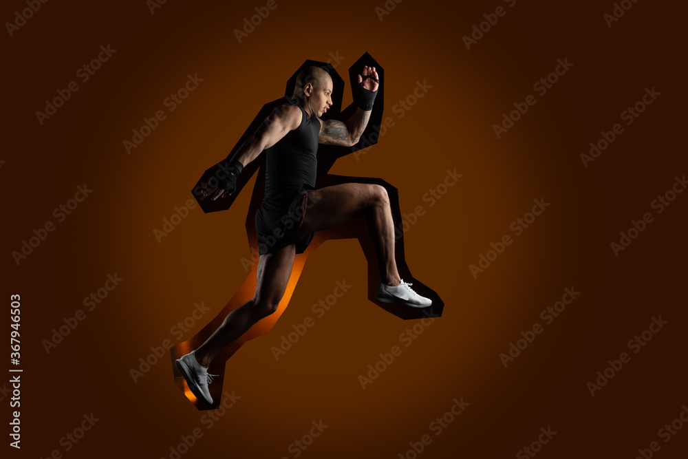 Determined male athlete running on dark orange background Determined male athlete running on dark orange background