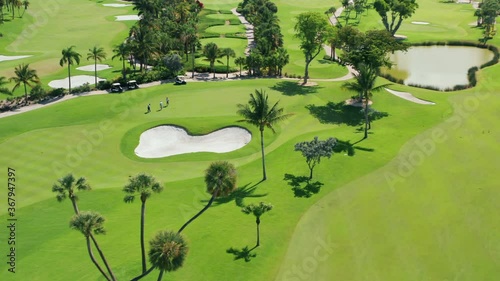 Cinematic overhead view on active men playing the golf game on a sunny summer day. Aerial footage of people on a golf course playing the sport match in Miami, Florida, USA. Background for business