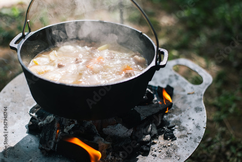 Preparing food on campfire in wild camping,Cooked food on a campfire on a camping trip. Camp kitchen, cooking food in the forest on fire. Frying pan on fire. Camping life concept.