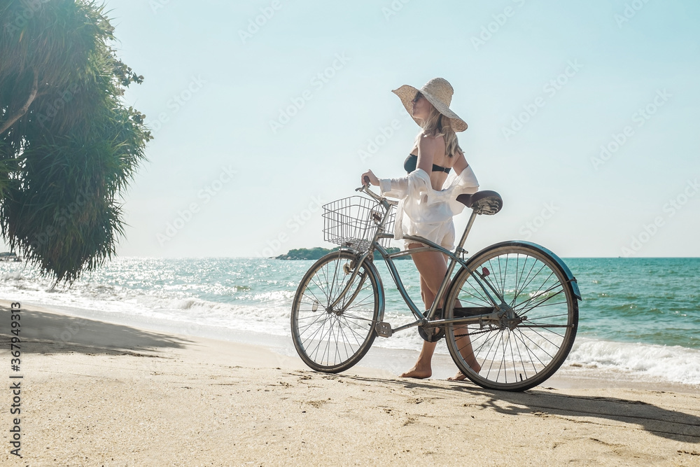 Fototapeta premium Happiness woman traveler with her bicycle rides on sea coastline
