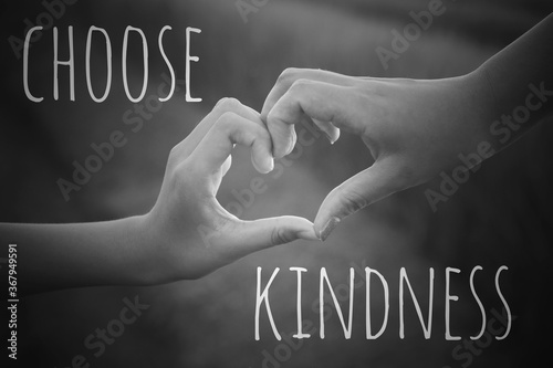 Inspirational quote - Choose kindness. With hands making love sign on black and white background. Being kind concept with heart-shaped hand and text message.