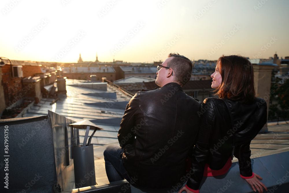 man and woman siting on rooftops historic center St. Petersburg and enjoying with amazing sunset. man and woman siting on rooftops historic center St. Petersburg and enjoying with amazing sunset.