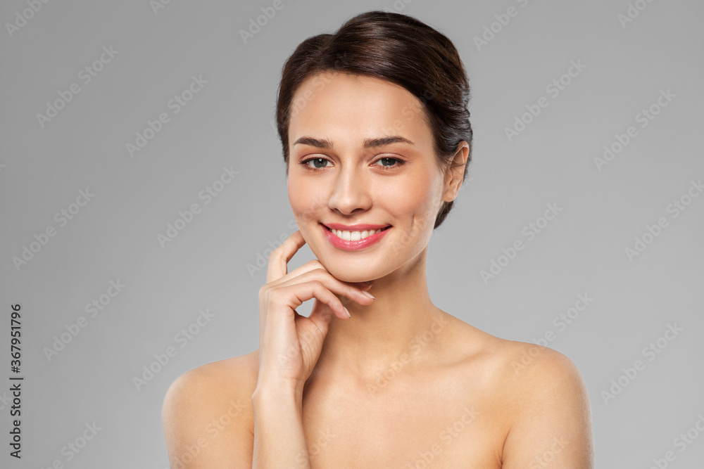 beauty, bodycare and people concept - beautiful young woman touching her face over grey background beauty, bodycare and people concept - beautiful young woman touching her face over grey background