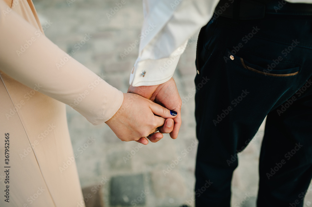 Cropped photo young married couple holds hands with rings, husband and wife outdoors. Rear view of couple standing on nature. Place for text and design. Summer in love.