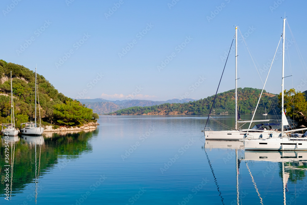Luxury yachts docked in sea port at sunset. A stunning view of mega yachts in the port. Mountains background. Luxury yachts docked in sea port at sunset. A stunning view of mega yachts in the port. Mountains background.