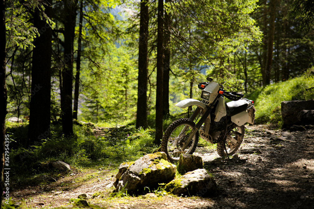 Mountain motorcycle standing on a cycling trail in the forest of alps mountains