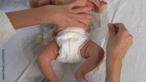 Mother changing diaper on her newborn baby.
