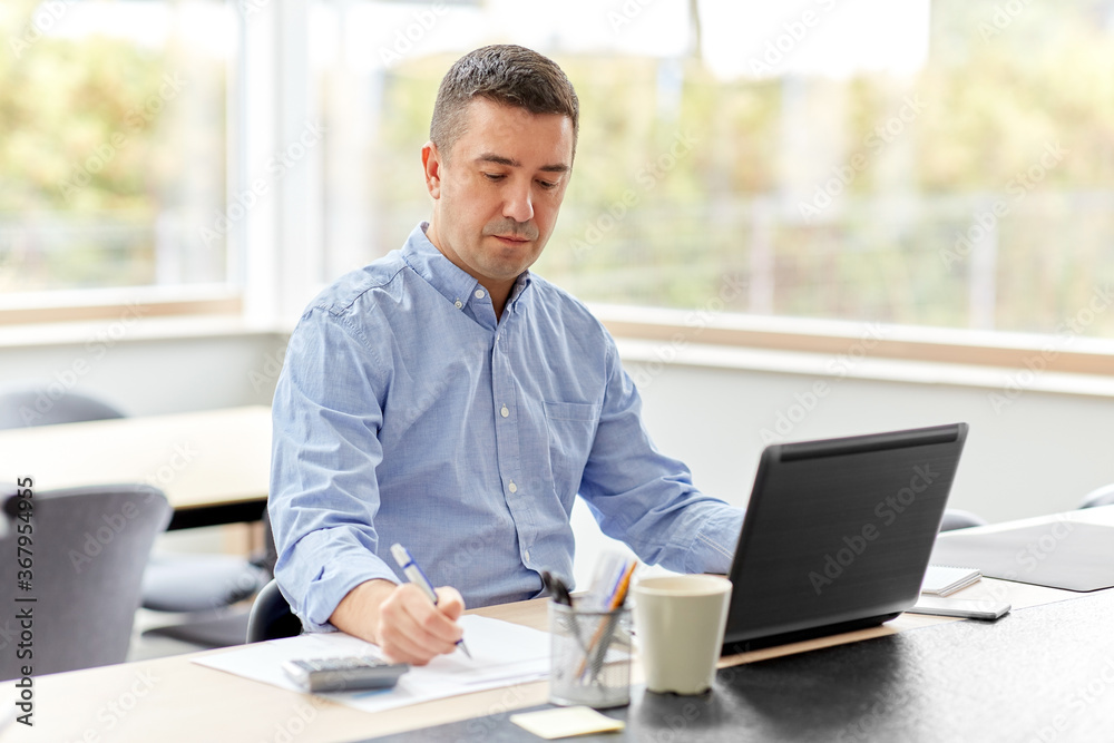 remote job, business and people concept - middle-aged man with calculator, papers and laptop computer working at home office remote job, business and people concept - middle-aged man with calculator, papers and laptop computer working at home office