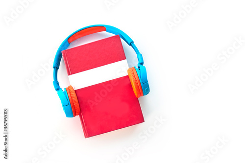 Audio book concept. Headphones and red book Top view with space for your text. Flat lay, top view, copy space