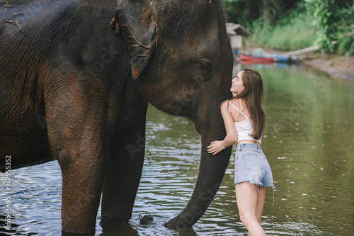 Canvas Print Portrait of woman tourist baths an elderly  asian elephant in  river at Elephant Nature Park in Kanchanaburi, Thailand