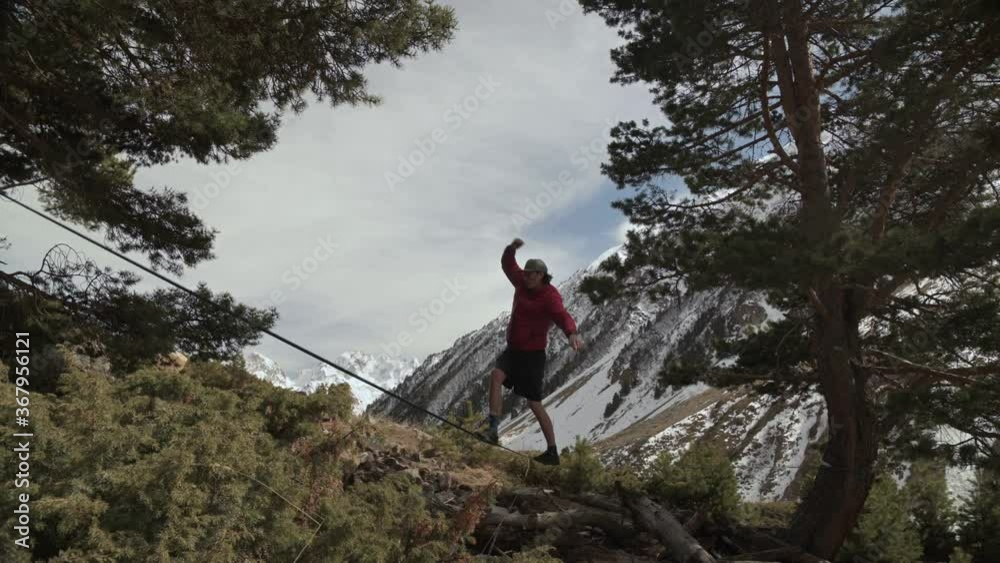 A young man teeters on a slackline in the mountains of the north Caucasus. Slackline en background of the mountains A young man teeters on a slackline in the mountains of the north Caucasus. Slackline en background of the mountains