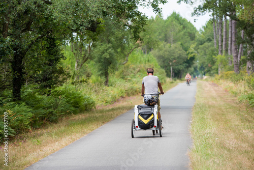 man riding a bicycle with his child trailer