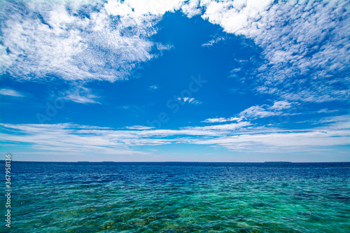 Turquoise sea with coral and circular cloud in the blue sky in a sunny day © Kapi
