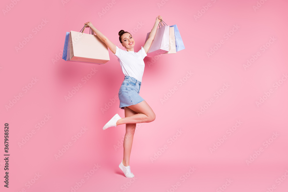 Full length photo of positive cheerful girl enjoy shopping raise many bags wear white t-shirt outfit gumshoes isolated over pastel color background