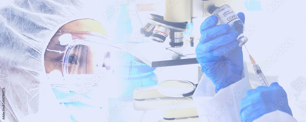 the doctor in protective virus suit looking corona virus vaccine in hand with microscope lab equipment background - obrazy, fototapety, plakaty 