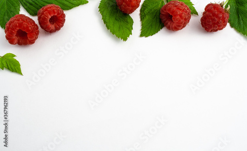 Ripe raspberries isolated on white background close-up. Beautiful red fresh raspberries with leaves along top contour on the table. Top view. Banner for web site. Free space for text