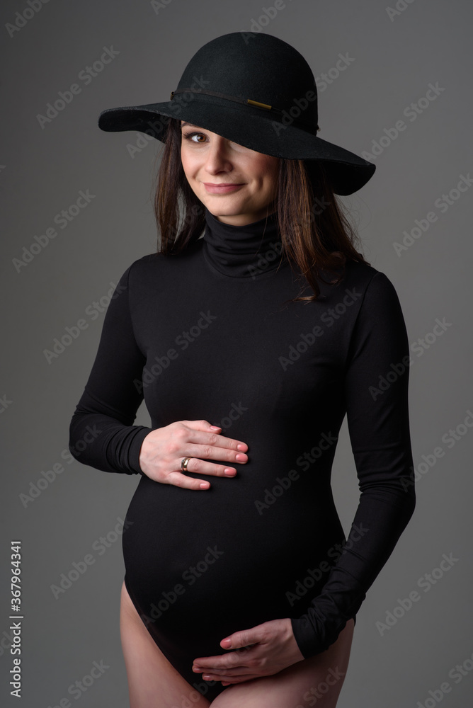 Young beautiful pregnant woman in black bodysuit and hat. Young beautiful pregnant woman in black bodysuit and hat.