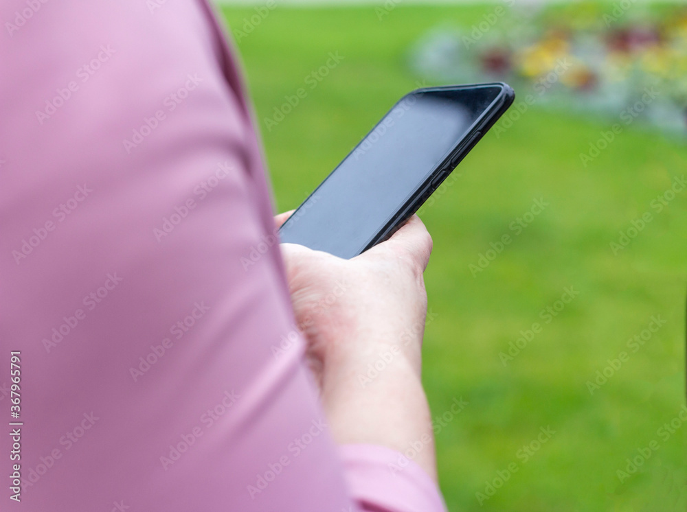 A girl in a summer Park holding a smartphone